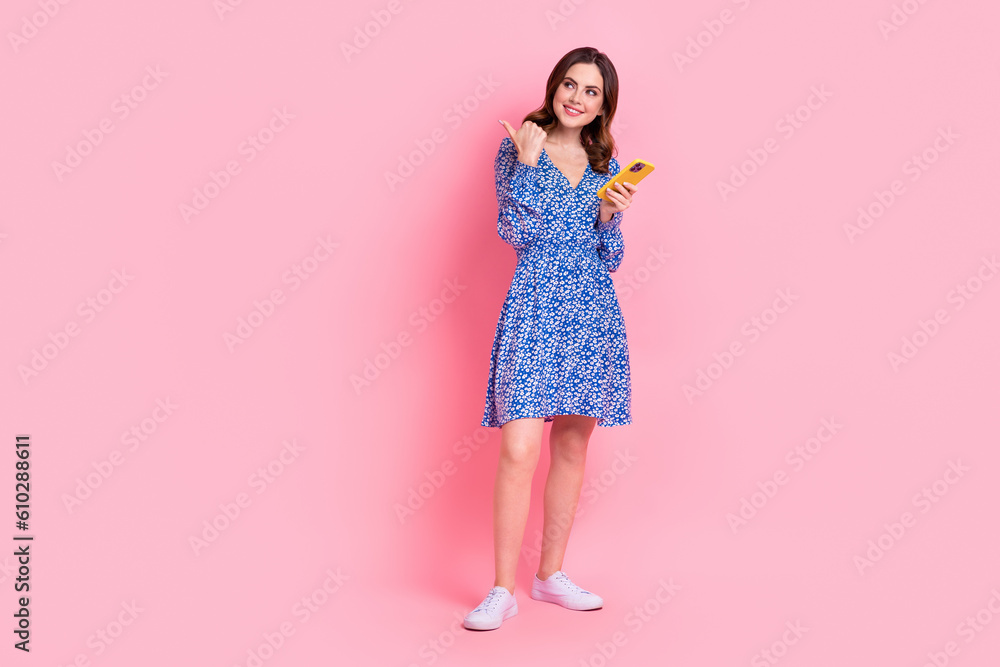 Full length photo of lovely lady wear trendy clothes thumb direct look empty space modern device shop isolated on pink color background Full length photo of lovely lady wear trendy clothes thumb direct look empty space modern device shop isolated on pink color background