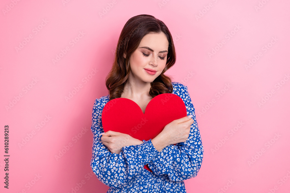 Photo of pretty positive person closed eyes hands hug hold red paper heart isolated on pink color background Photo of pretty positive person closed eyes hands hug hold red paper heart isolated on pink color background