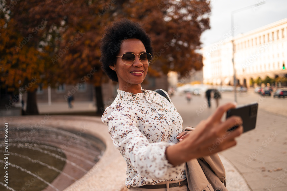 Smiling woman holding a mobile phone and taking photos of herself.