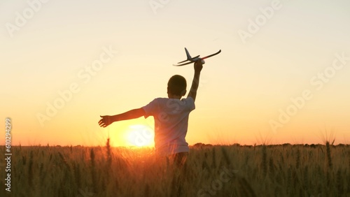 boy teenager child kid runs through field with wheat with toy plane his hands sunset, happy dream family, child wants become pilot pilot astronaut, holding airplane his hands, pilot flight astronaut photo