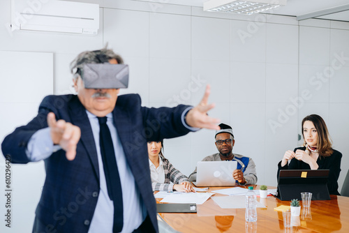 Adult businessman showing young people in his company how to use VR glasses.