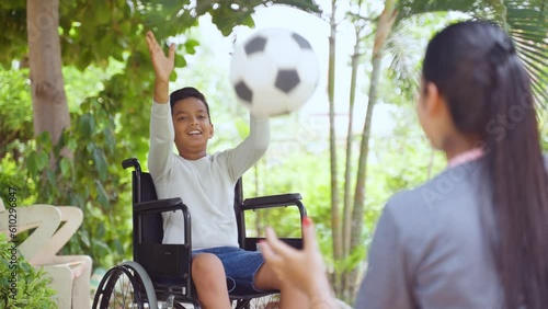Shoulder shot of indian mother playing with son with disability on wheelchair at park - concept of supportive parent, family bonding and aspiration