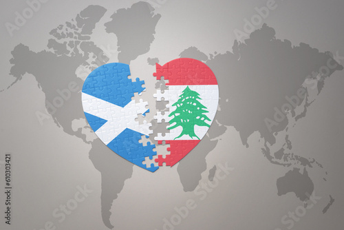 puzzle heart with the national flag of lebanon and scotland on a world map background.Concept. photo