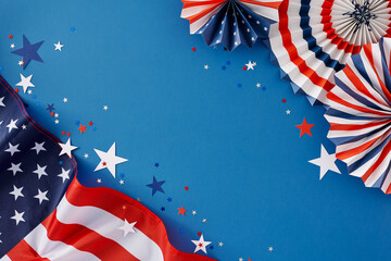 4th of July celebration theme. Top view flat lay of american flag, paper party decorations, confetti in national colours on blue background with empty space for message or ad