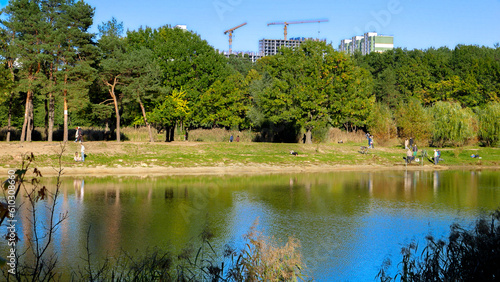 People relaxing at the lake in city park on sunny autumn day