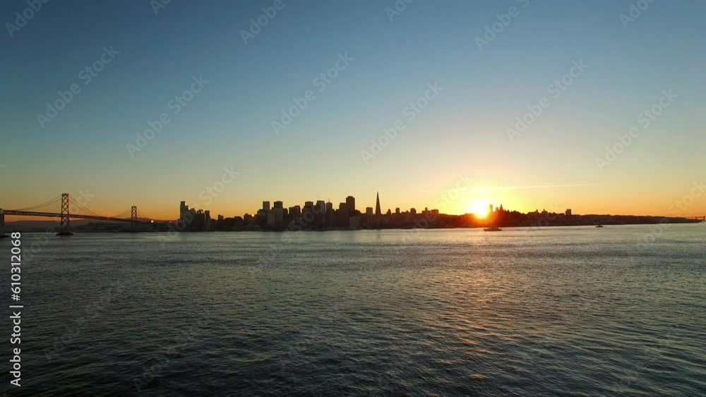 Aerial: Drone Flying Backward From Silhouette Skyscrapers In City Near Oakland Bay Bridge On Sea Against Sky At Sunset - San Francisco, California Aerial: Drone Flying Backward From Silhouette Skyscrapers In City Near Oakland Bay Bridge On Sea Against Sky At Sunset - San Francisco, California