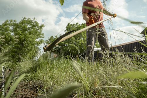 Obraz na plátně Farmer mowing the grass with classic scythe during hot summer day