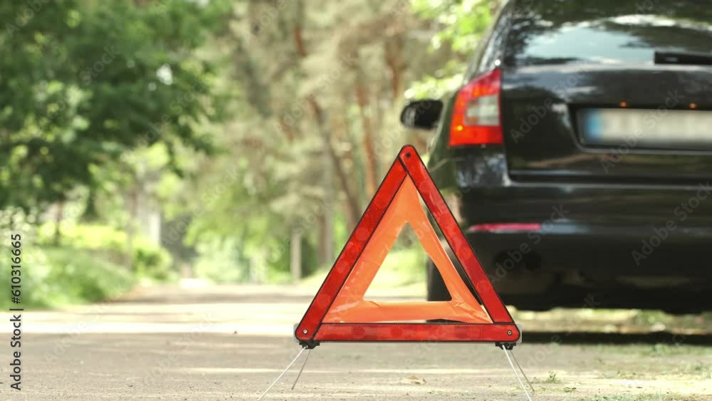 Red triangle, red emergency stop sign and black car with turned on