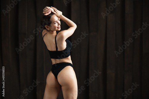 Portrait of a fit young woman posing wearing a sports bra against dark background. Determined athlete