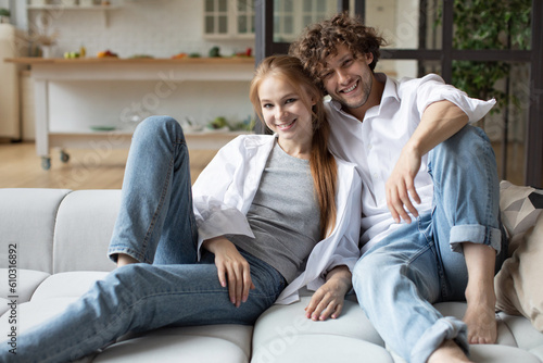 Smiling young couple relaxing and watching TV on sofa at home.