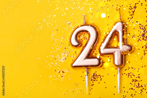 24 years celebration. Greeting banner. Gold candles in the form of number twenty four on yellow background with confetti. photo