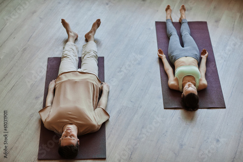 Vászonkép Top view at two young people lying down on floor in meditation with eyes closed,