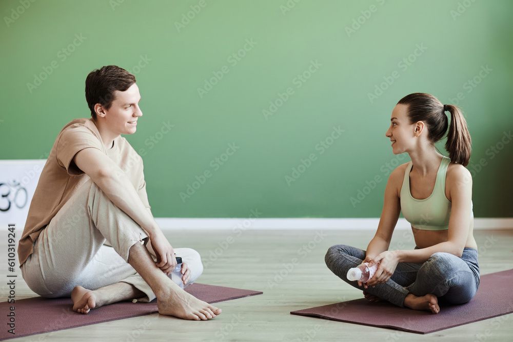 Full length portrait of young couple chatting after working out together indoors, copy space Full length portrait of young couple chatting after working out together indoors, copy space