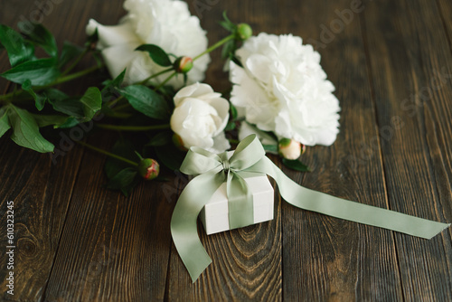 Bouquet of beautiful white peonies with gift boxes on wood background. Stylish floral greetings. Mothers day