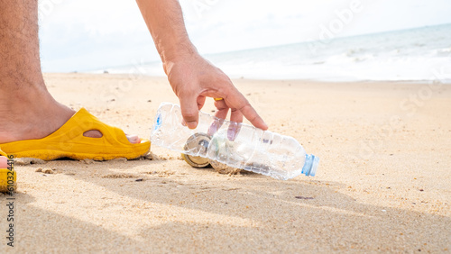 Hand picking up plastic bottle cleaning on the beach. Save the world concept. Environment, ecology care, renewable concept,Nature conservation tourism