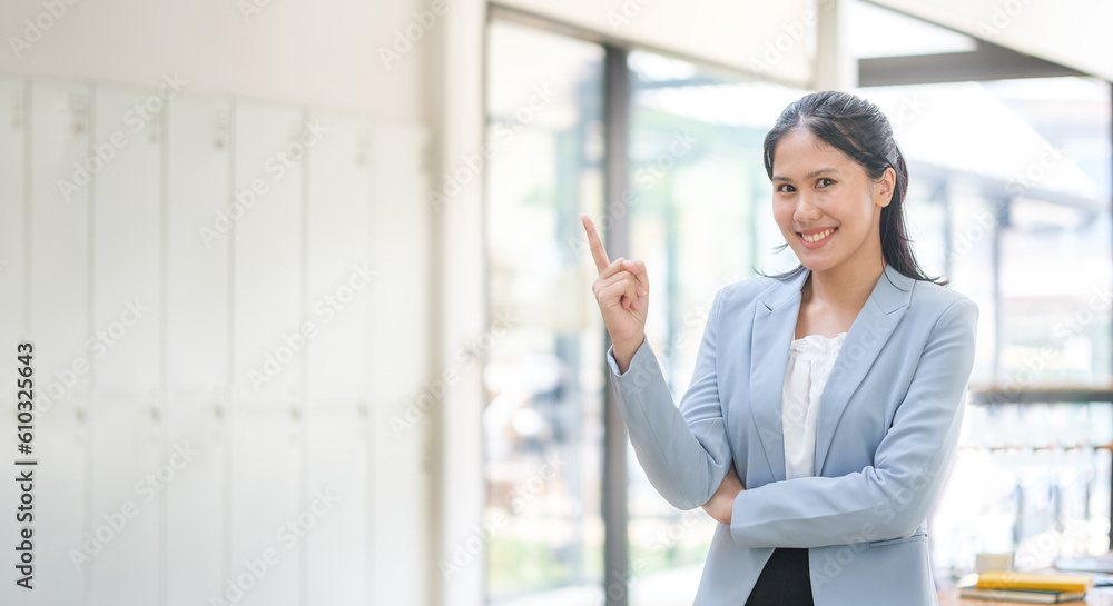 Successful businesswoman standing in modern office and pointing at copy space. Successful businesswoman standing in modern office and pointing at copy space.
