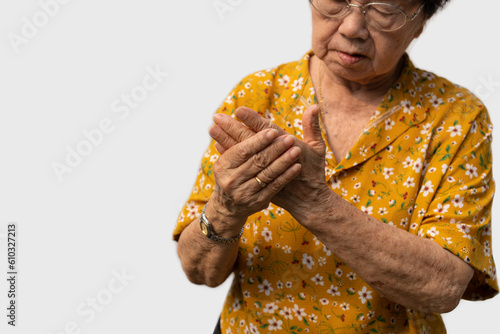 Elderly Asian woman patients suffer from numbing pain in hands from rheumatoid arthritis. Senior woman massage her hand with wrist pain. Concept of joint pain, rheumatoid arthritis, and hand problems. photo