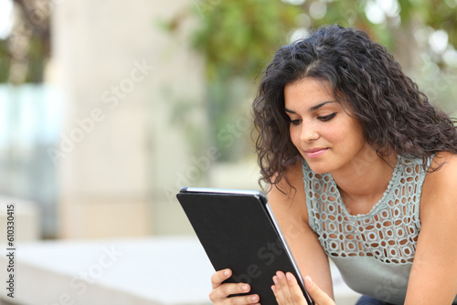 Woman using tablet sitting on a bench in a park