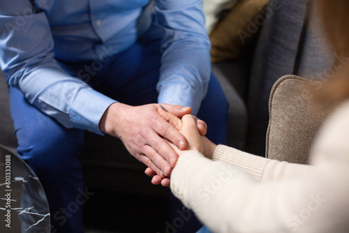 Specialist shows support for patient on therapy session. Female psychologist holds male person hands and helps to overcome stress