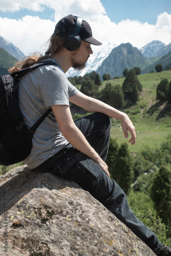 Naklejka premium Young man in summer mountains at sunset and enjoying view of nature. Happy hiker, life goal, success, freedom and happiness.