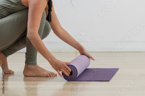 Close up of the hands of a young woman rolling up her mat after practicing yoga