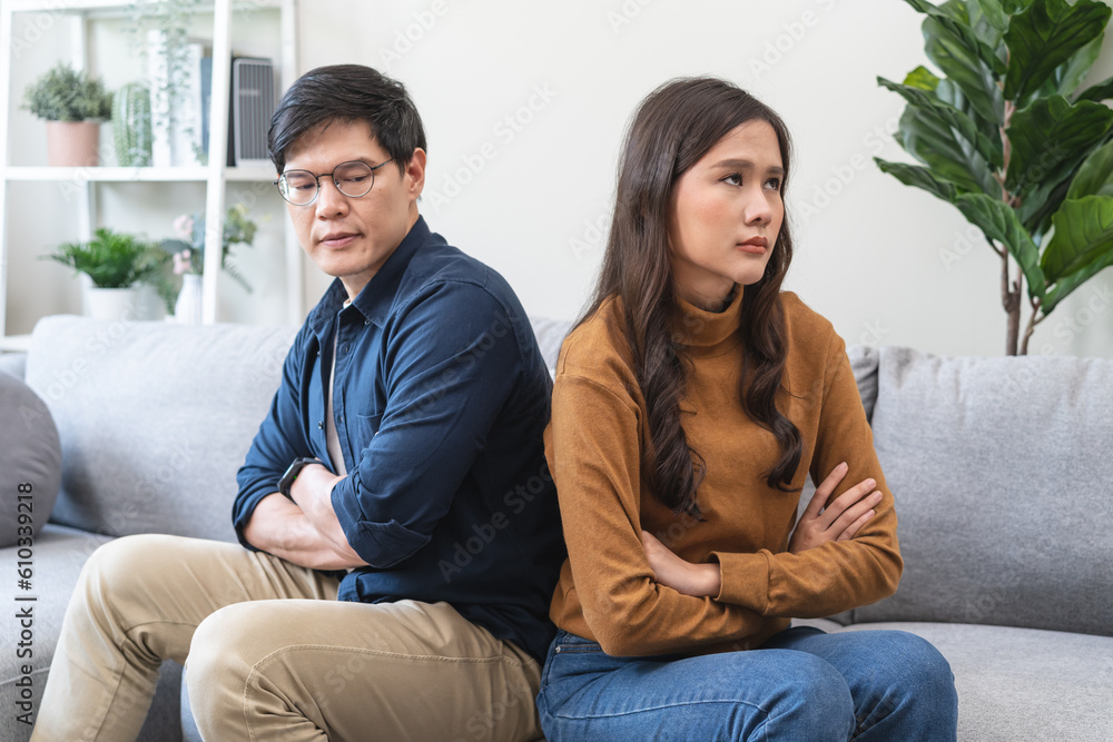 Family problem concept, Asian wife and husband sitting back to back in the living room at home have problems in a relationship and have an argument Family problem concept, Asian wife and husband sitting back to back in the living room at home have problems in a relationship and have an argument