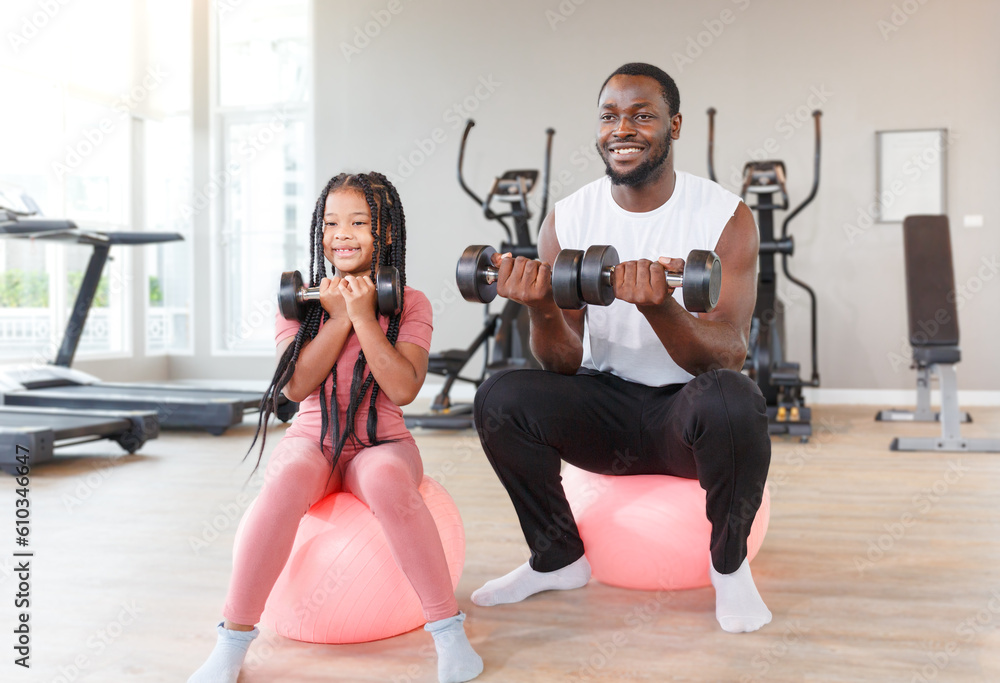 Father teaches, trains daughter to lift dumbbells, cute, smiling, cheerful and happy.