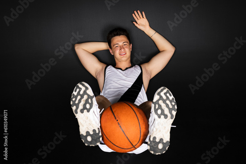 Handsome young basketball player in white sportswear. Isolated on black background.