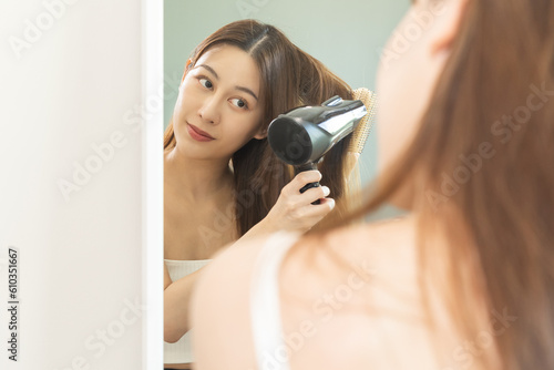 Hair Dryer, happy, asian young woman, girl looking into mirror reflect using hairdryer to dry, blowing long blonde straight after shower at home. Hairdressing, hair treatment and beauty health care.