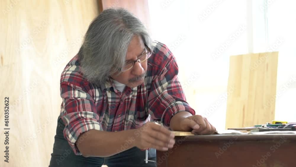 Lifestyle aging people with hobby after retirement concept, Asia elderly man focuses on his work at carpentry home studio, man working with his DIY handmade woodwork, aged people having fun with work Lifestyle aging people with hobby after retirement concept, Asia elderly man focuses on his work at carpentry home studio, man working with his DIY handmade woodwork, aged people having fun with work