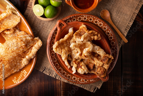 Chicharron. Crispy Fried pork rind, are pieces of aired and fried pork skin, traditional Mexican ingredient or snack served with lime juice and red hot sauce. photo
