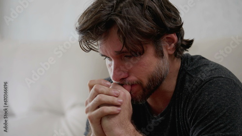Remorseful young man in his 30s feeling overwhelmed with sadness and emotional pain while reflecting on his past