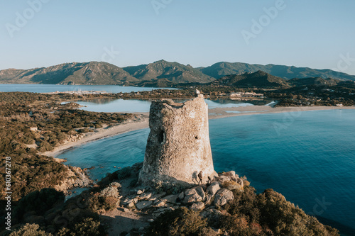 Der Torre di Porto Giunco zum Sonnenaufgang. Turm auf einem Hügel mit türkisblauen Wasser im Norden von Sardinien. Drohnne 1