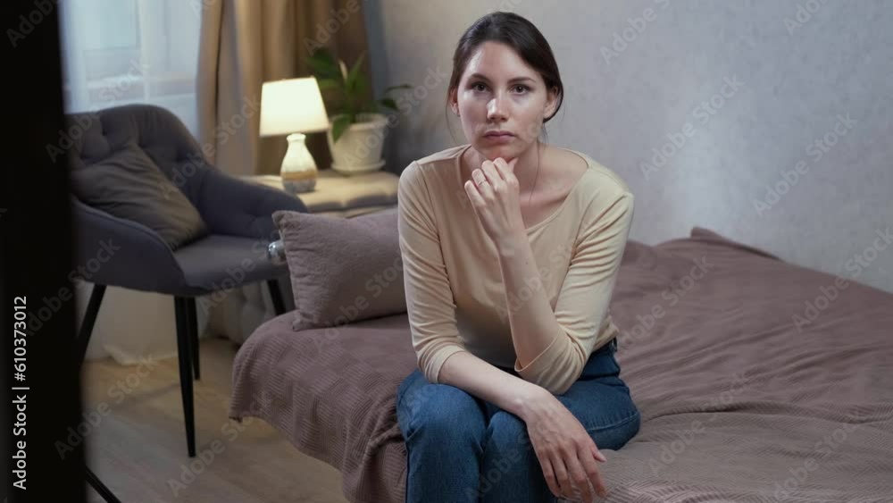 A young attractive Caucasian woman, sad and offended, is sitting on the sofa. Turns his head with sad eyes A young attractive Caucasian woman, sad and offended, is sitting on the sofa. Turns his head with sad eyes