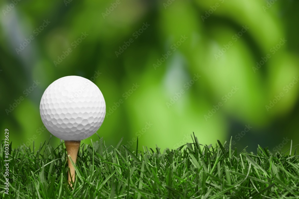 White golf ball on wooden tee with grass White golf ball on wooden tee with grass