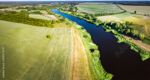 The view has fields, meadows, forests and a river from above. Greater Poland Voivodeship. Drone aerial