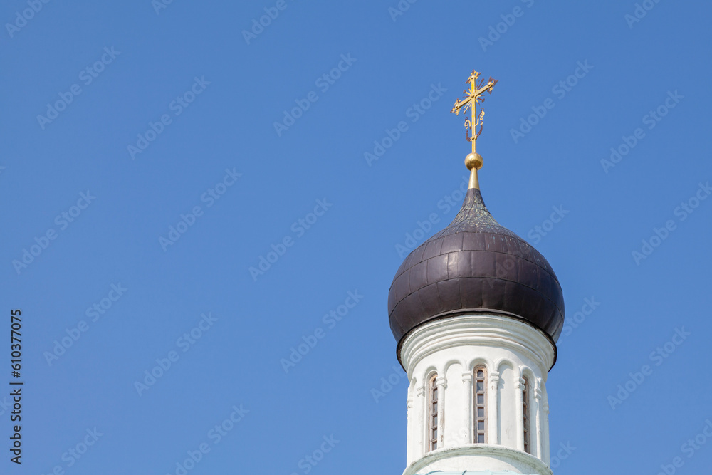 The dome of an Orthodox church in black against a clear blue sky