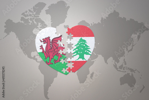 puzzle heart with the national flag of lebanon and wales on a world map background.Concept. photo