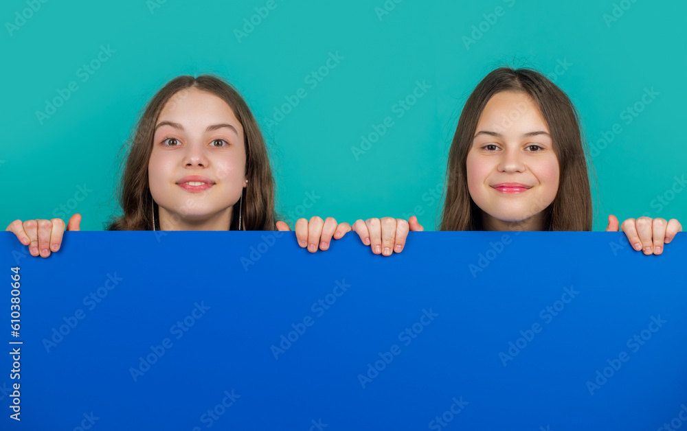 cheerful children behind blank blue paper with copy space for advertisement cheerful children behind blank blue paper with copy space for advertisement