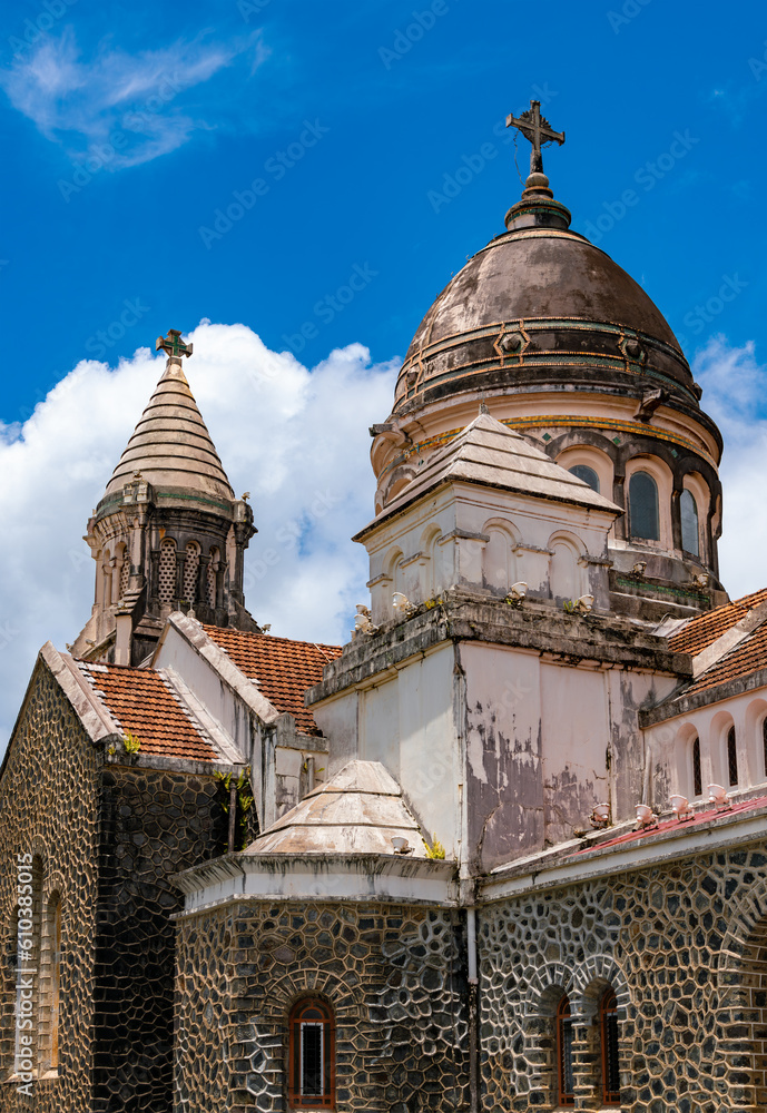 Fototapeta premium Weathered and colorful dome or cupola of “Sacré-Coeur de Balata“, church (1915) near Fort-de-France, capital of Martinique island, . Christian monument and tourist attraction in tropical landscape.