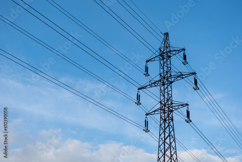 The low-angle view of a transmission tower with electric wires under the blue sky