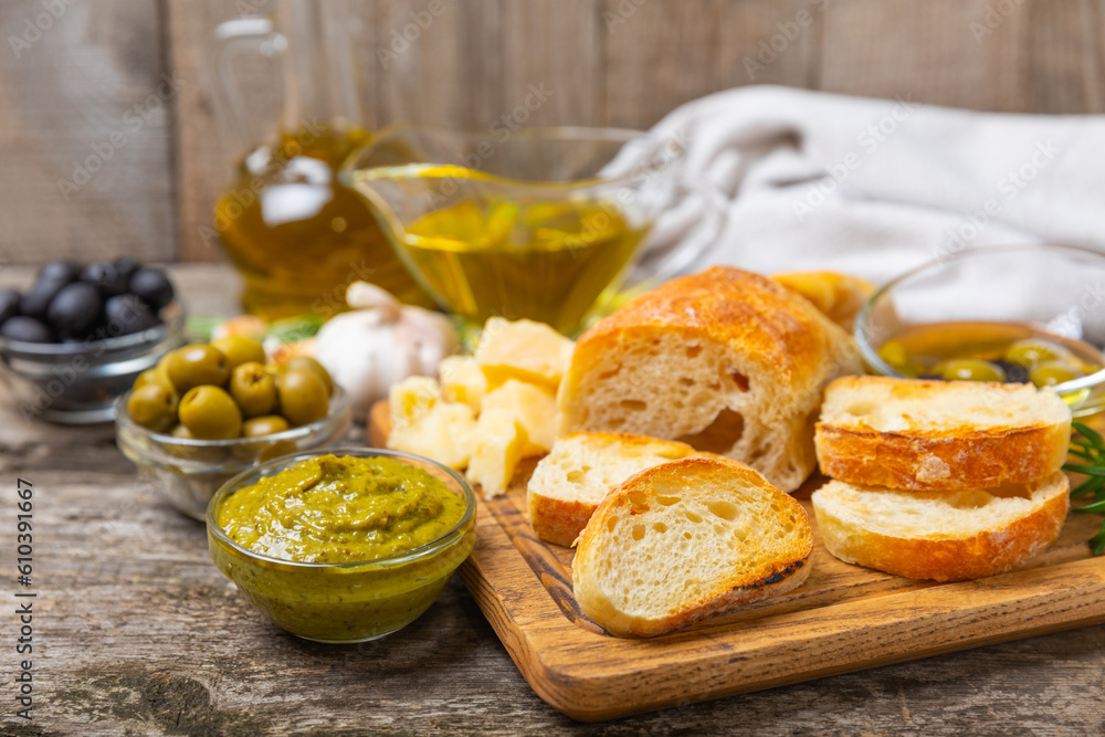 Italian ciabatta bread cut in slices with herbs, olives, pesto sauce, garlic and parmesan cheese on a wooden table. Fresh homemade Italian Ciabatta bread sliced with herbs and spices.Place for text. 