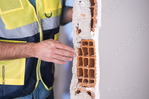 Architect in professional uniform checking wall construction material in hand preparing for renovation construction quality control and earthquake-resistant reinforcement photo