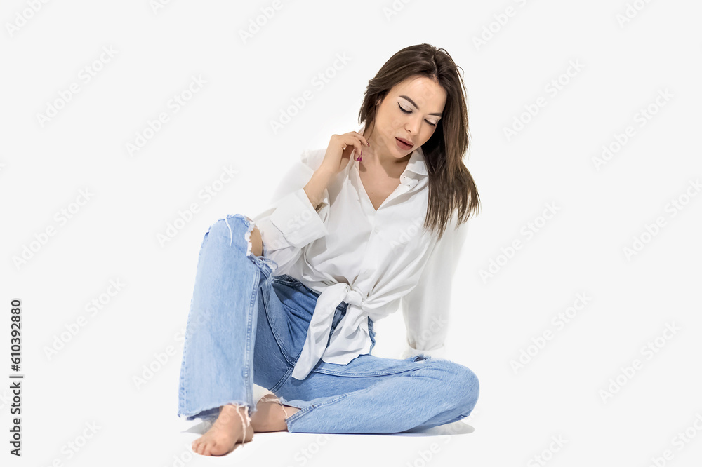 A beautiful sexy brunette with long hair in a black bodysuit, jacket and boots poses on a white background. Studio shooting A beautiful sexy brunette with long hair in a black bodysuit, jacket and boots poses on a white background. Studio shooting