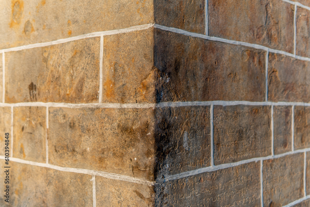 Corner of a stone wall with one side lit by the sun and the other side ...