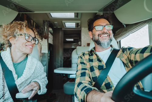Happy vanlife tourism lifestyle people driving and enjoying vacation together inside a camper van in front interior view. Happiness and freedom concept lifestyle couple. Man and woman using motorhome