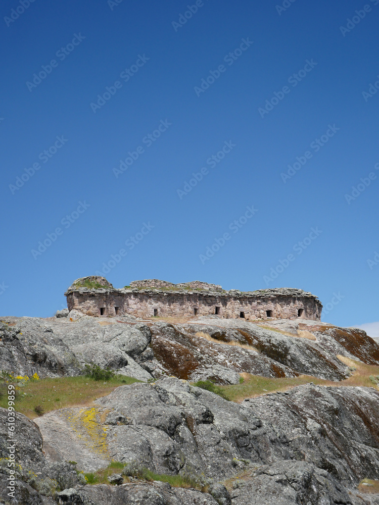 Fototapeta premium Marcahuasi chullpas, house made with stones on the top of a rocky mountain, archaeological remains in the mountains with a background of blue sky in South America