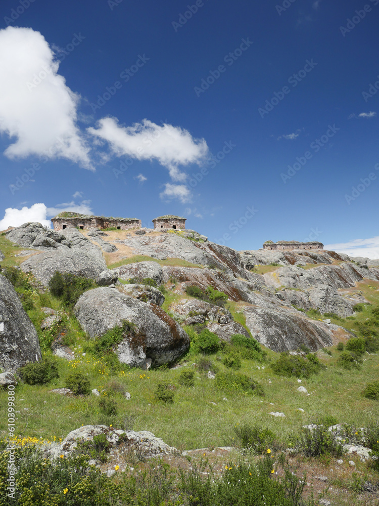 Marcahuasi chullpas, house made with stones on the top of a rocky mountain, archaeological remains in the mountains with a background of blue sky with clouds in South America