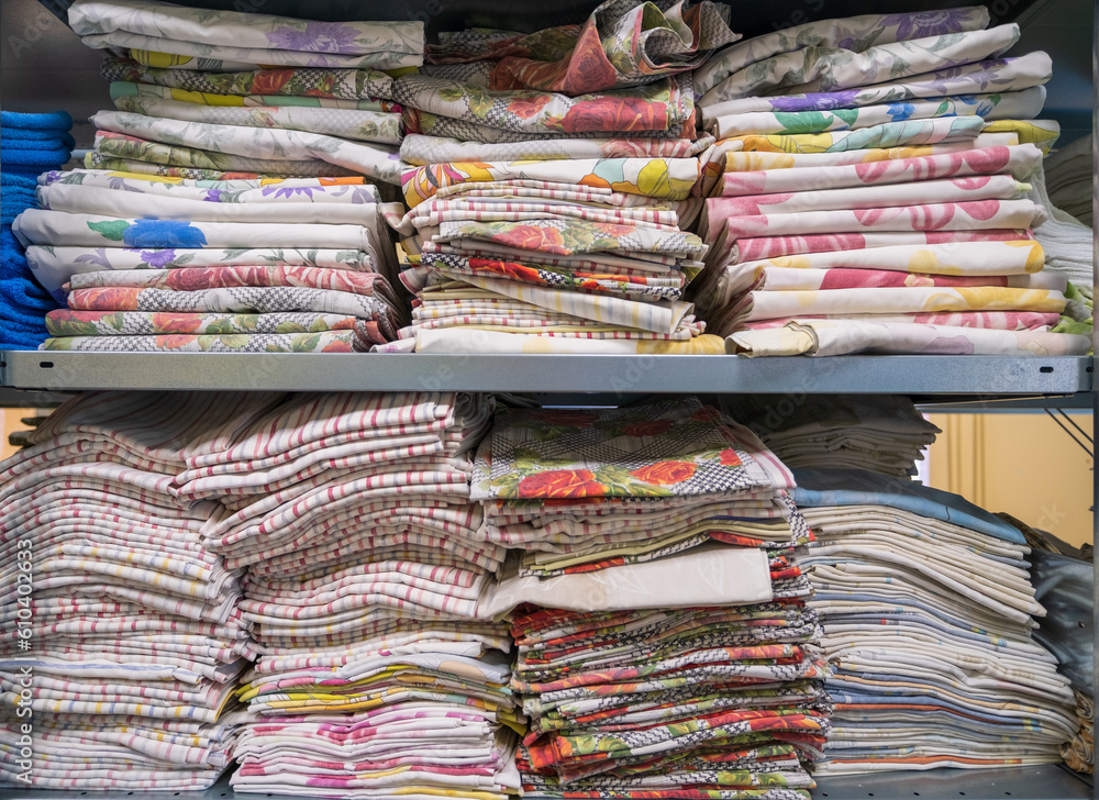 A pile of folded clean sheets or fabrics in an industrial laundry. Services for hotels, hospitals, clinics and companies.