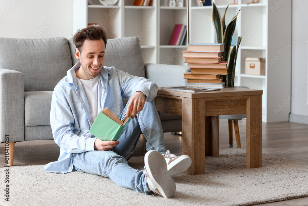 Young man reading book on floor at home